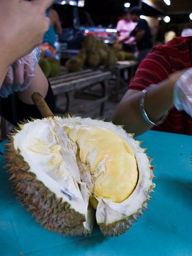 A Durian, cut open in a market to expose its custard yellow flesh