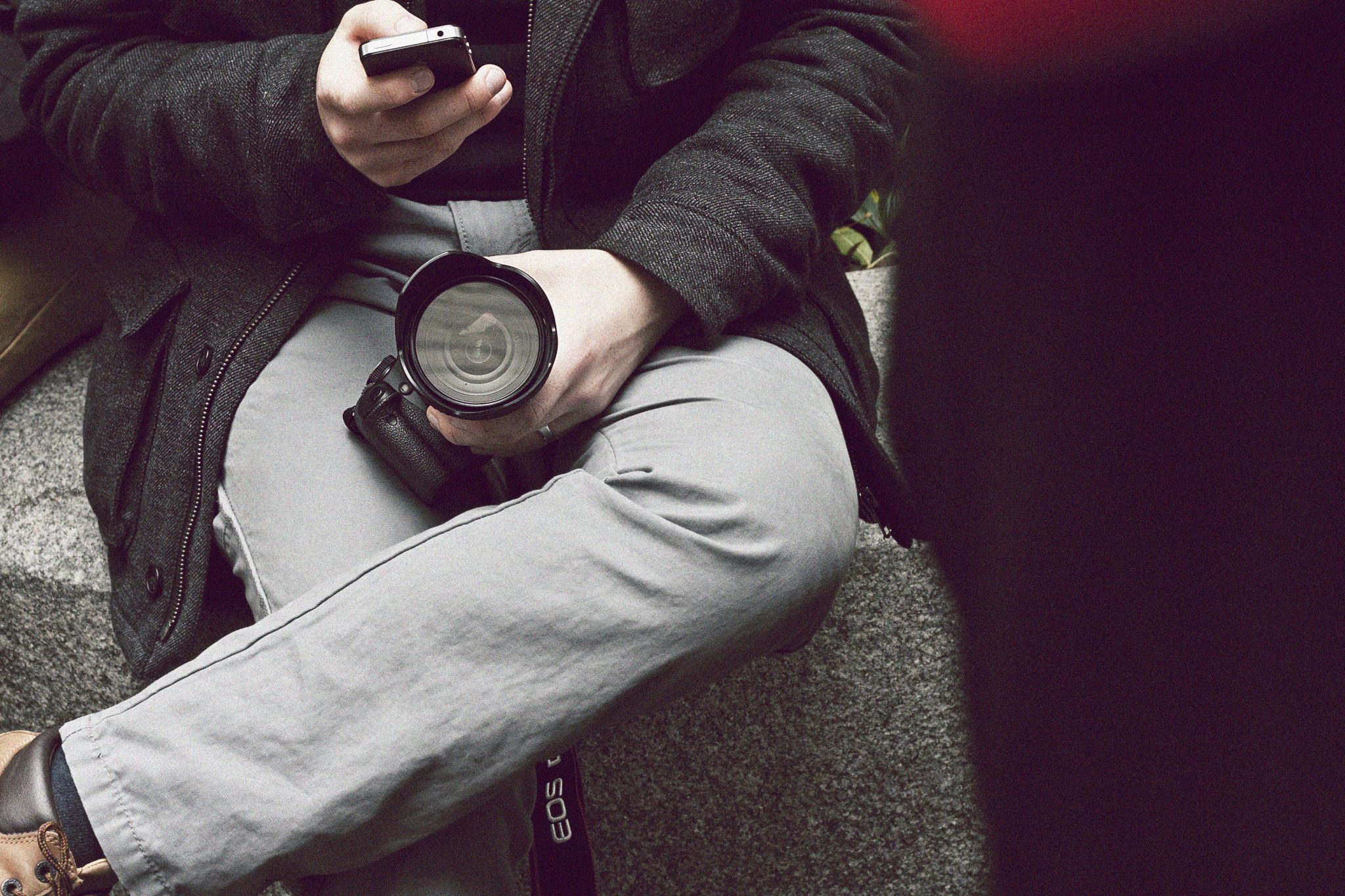 Man holding a camera, staring at his phone