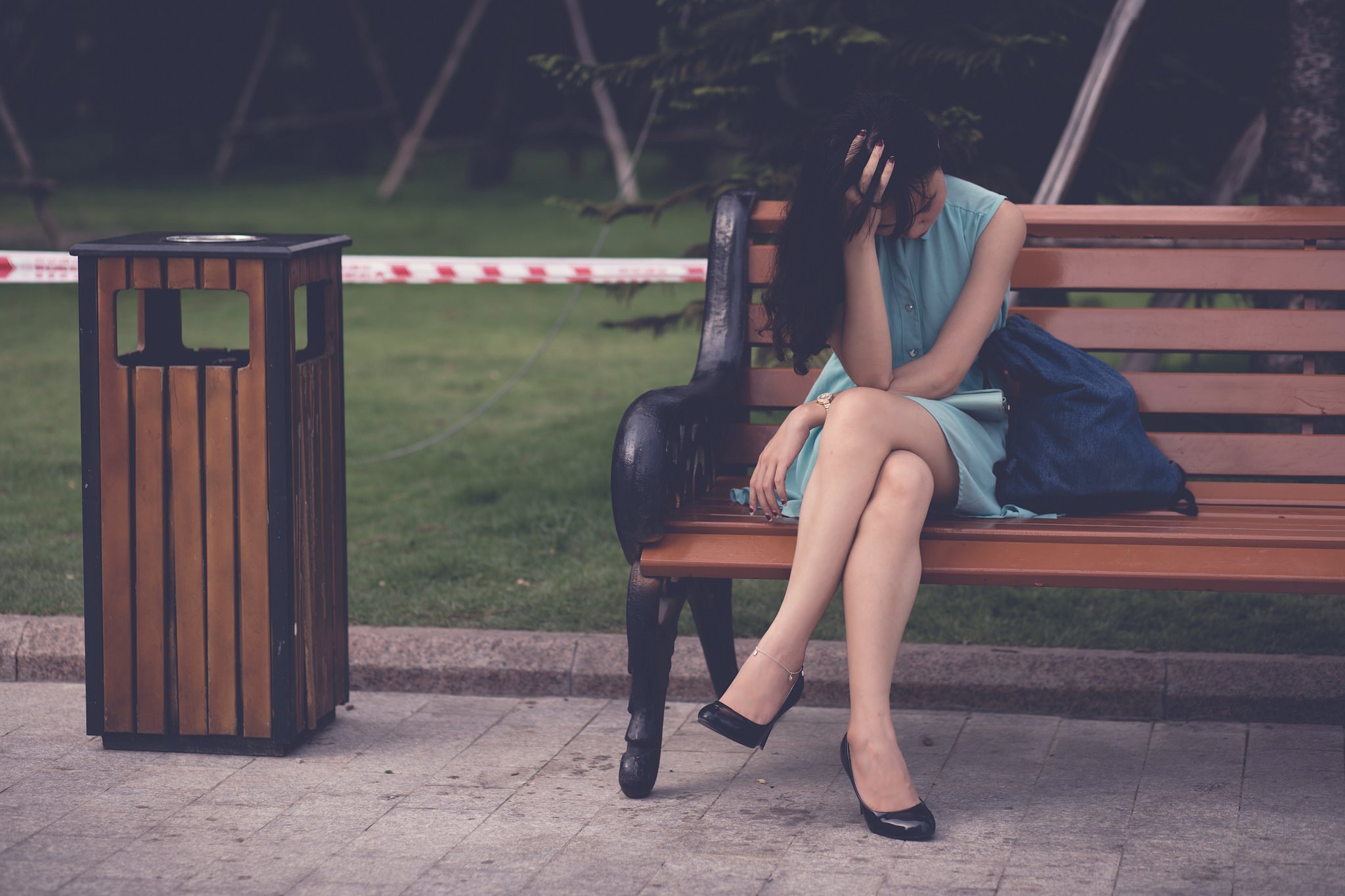 Woman sitting with her head in her hands on a park bench