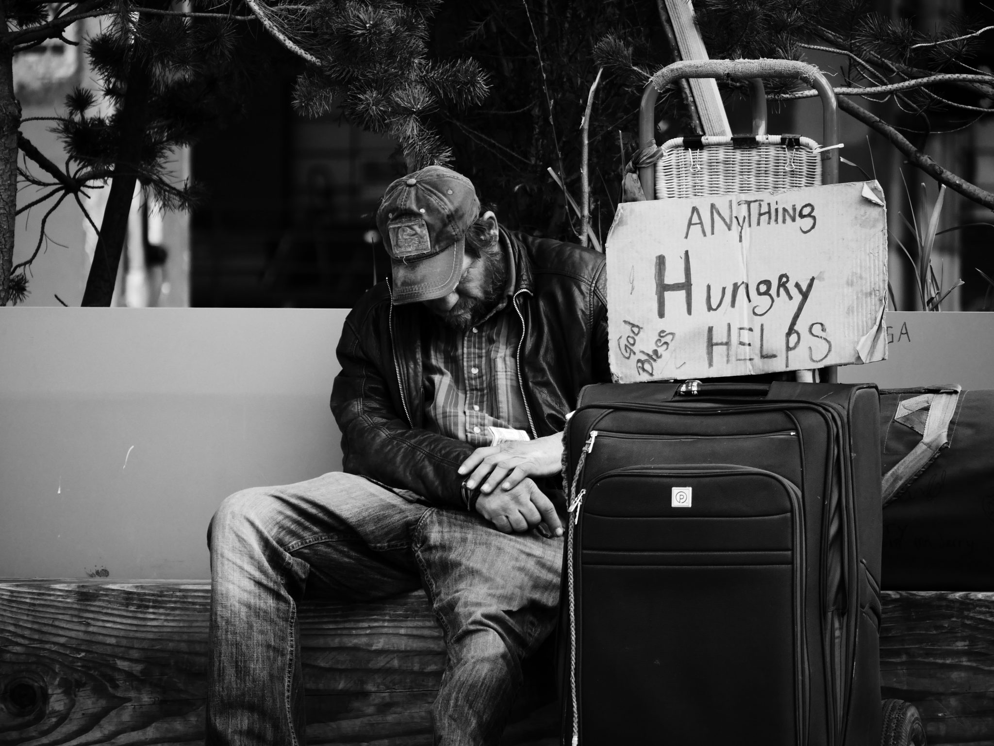 homeless man with his head down, sign that says "hungry, anything helps"