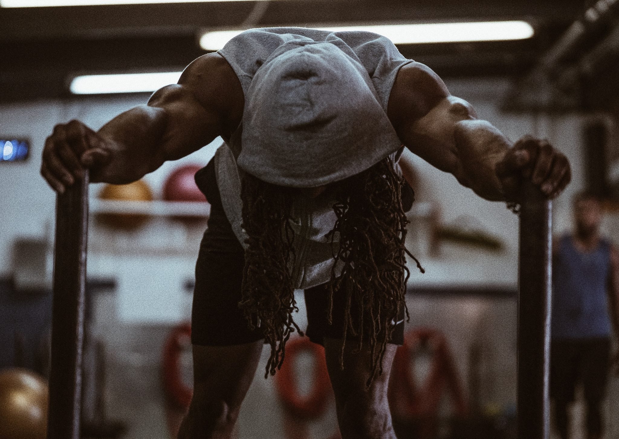 man in gym, leaning forward with hands on poles