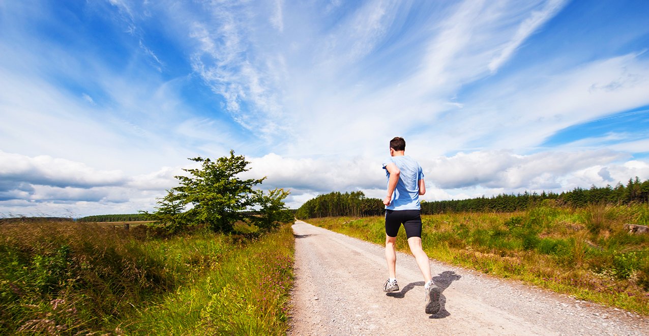 Man running on road near grass field